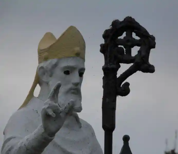 A statue holding a crosier, the crosier having a solar cross